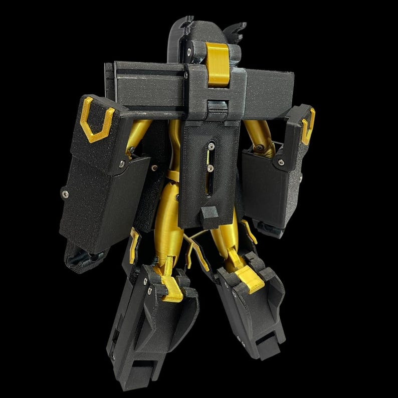 May include: A black and gold robot toy with articulated joints. The robot has a boxy design with gold accents on the arms, legs, and head. The toy is standing against a black background.