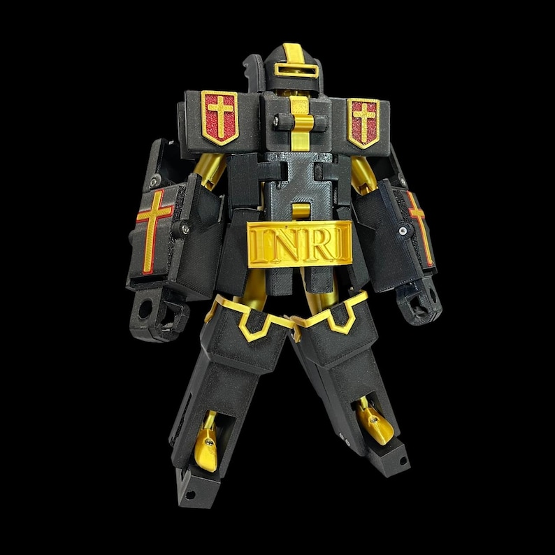 May include: A black and gold robot toy with religious symbols. The robot features crosses on its chest and arms, with the letters "INRI" across its midsection. Gold accents and red crosses contrast against the black body.