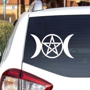 May include: White vinyl car decal featuring a triple moon symbol with a pentagram in the center. The decal is applied to the rear window of a white vehicle, with the taillight visible.