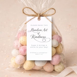 May include: A clear cellophane bag tied with twine, filled with pastel-colored speckled candies. A white tag reads "Please Enjoy This Random Act of Kindness" with a heart and the message "hope it brings a smile to your day!"