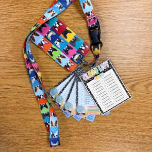May include: A vibrant lanyard and cardholder set, patterned with repeating dog faces. The lanyard has a black plastic clasp. A small notepad with a class list is also included.