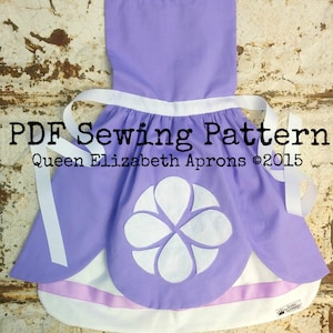 May include: A lavender apron with white trim, straps, and a large floral design on the front. The apron has a ruffled neckline and a white ribbon. Text on the apron reads "PDF Sewing Pattern" and "Queen Elizabeth Aprons ©2015".