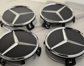 Peut inclure: Quatre enjoliveurs noirs et argentés avec le logo Mercedes-Benz. Chaque enjoliveur présente un centre noir avec un emblème en étoile à trois branches argenté, entouré d'une jante argentée. Conçus pour l'automobile.