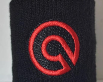 Peut inclure: Bandeau de poignet noir avec un motif circulaire rouge brodé. Le bandeau est fait d'une matière épaisse et absorbante, probablement pour les activités sportives ou de fitness. Le motif rouge est une lettre "G" stylisée.