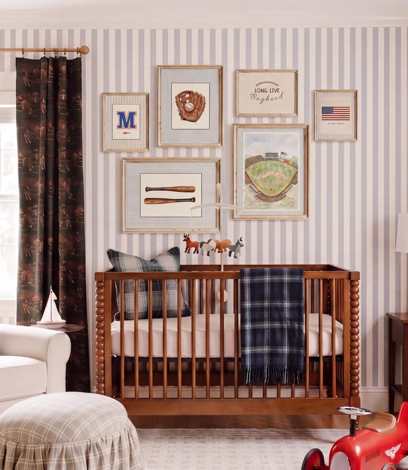 May include: A wooden crib with a dark blue plaid blanket and a gray plaid pillow, positioned against a wall with six framed baseball-themed prints, including a glove, bats, a stadium, and the text Long Live Boyhood and an American flag.