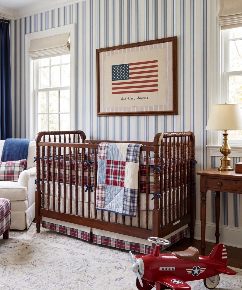 May include: A dark wood crib with a red, white, and blue plaid quilt and matching bumper. A framed print of the American flag with the text God Bless America hangs above. A red toy airplane sits on the floor in front of the crib.