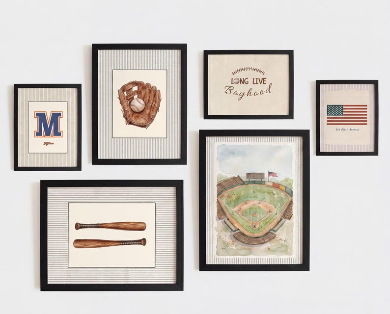 May include: A gallery wall set of six black-framed prints featuring baseball-themed illustrations. The artwork includes a letter M, a baseball glove with a ball, two wooden bats, a stadium view, an American flag, and the text Long Live Boyhood.