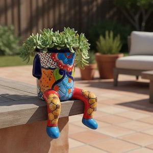 May include: A ceramic planter shaped like a seated figure with dangling legs, featuring a vibrant Talavera-style pattern in red, blue, orange, and green. The cylindrical body is filled with a green succulent plant, and the legs are decorated with yellow flower motifs and solid blue feet.