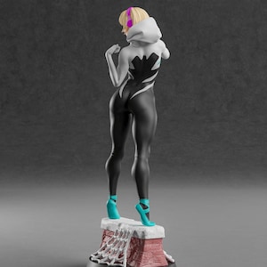 K&ouml;nnte beinhalten: Figur einer Superheldin in einem schwarz-wei&szlig;en Body mit Kapuze, die auf einem ziegelartigen Sockel steht. Die Figur hat blondes Haar, ein rosa Stirnband und t&uuml;rkisfarbene Schuhe. Der Sockel hat ein Spinnennetz-Design.