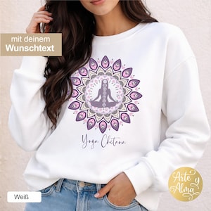 Könnte beinhalten: Weißes Sweatshirt mit einem Mandala-Design in Lila und Rosa, das eine sitzende Figur zeigt. Die Worte "Yoga Chitana" sind darunter in Schreibschrift geschrieben. Das Sweatshirt hat einen Rundhalsausschnitt.