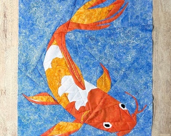 May include: A colorful patchwork quilt featuring a large orange and yellow koi fish swimming in a blue and white swirl pattern.