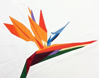 May include: A paper craft of a bird of paradise flower. The flower is made of orange, red, yellow, green, blue, and purple paper. The flower is on a white background.