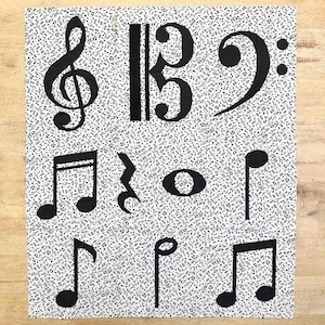 May include: Black and white fabric with a repeating pattern of musical notes. The fabric features larger musical symbols, including a treble clef, bass clef, a quarter note, a half note, an eighth note, a whole note, and a sharp symbol.