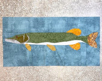 May include: A patchwork quilt depicting a green and white fish with yellow fins and a brown tail. The fish is swimming in a blue background.