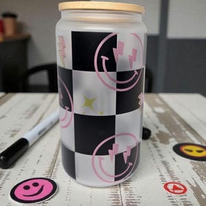 Vaso de café helado de cristal con cara sonriente a cuadros / Tapa y pajita de bambú