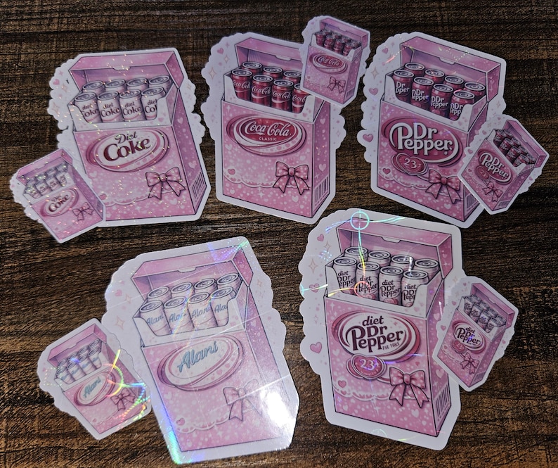 May include: Pink stickers featuring boxes of soda cans designed to look like cigarette packs. The boxes are decorated with bows and the soda brands Diet Coke, Coca-Cola, Dr. Pepper, and Alan's are visible.