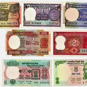 Puede incluir: Colección de billetes de banco indios con denominaciones de 1, 2 y 5 rupias. Los billetes muestran varios colores, incluyendo verde, rojo y morado, con imágenes de monedas, el emblema indio y retratos. Los billetes están en varias condiciones.
