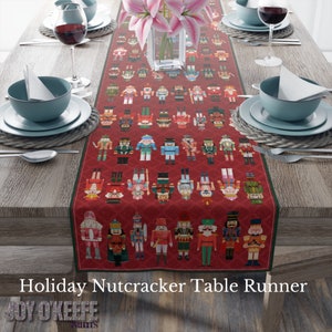 May include: Red table runner with a repeating pattern of colorful nutcracker figurines. The runner is on a wooden table with two place settings.