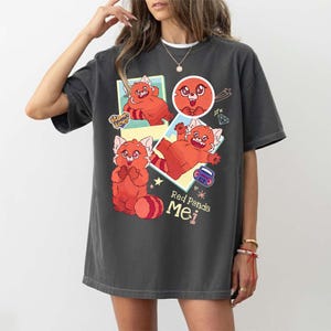 Può includere: T-shirt grigio scuro con un design a cartone animato di panda rosso. La grafica include il testo "Red Panda Mei" e altre illustrazioni. La maglietta ha un girocollo e maniche corte.