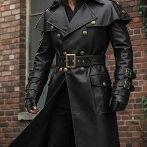 Puede incluir: Abrigo largo de cuero negro con diseño de doble botonadura, botones dorados y cinturón a juego. El abrigo tiene un detalle de hombro tipo capa y se usa con guantes negros. El estilo general evoca una estética militar o steampunk.
