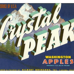 May include: Vintage fruit crate label for "Crystal Peak" Washington apples. The label features a stylized mountain scene with the words "Crystal Peak" in large, 3D lettering. The text "Produce of U.S.A." and "Washington Apples" are also included.