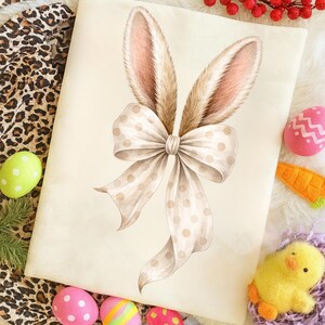 May include: Watercolor illustration of bunny ears with a polka dot bow. The ears are brown with pink inner ears. The bow is cream-colored with brown polka dots. Easter-themed image with decorative eggs, a carrot, and a chick.