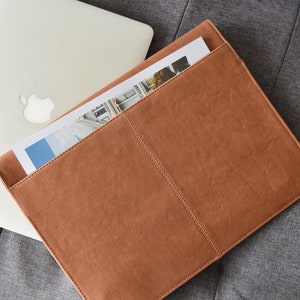 Caramel brown leather laptop sleeve with rear document pocket—minimalist MacBook case for travel and office.