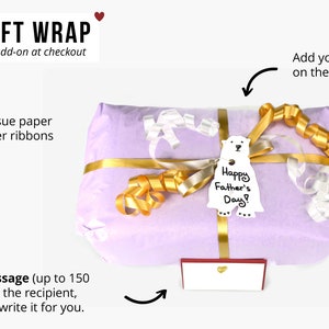 May include: A wrapped gift in lavender tissue paper, adorned with gold and silver ribbons. A bear gift tag says "Happy Father's Day!" A small gift card is included. The text "ADD A GIFT WRAP" is at the top.
