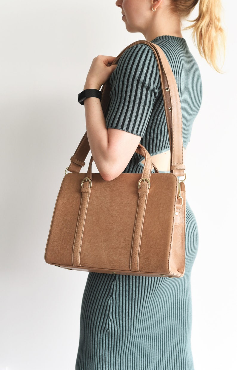 Woman carrying light brown leather handbag on shoulder – structured full grain leather work bag with crossbody strap.