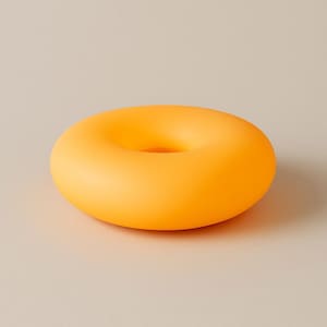 Op de afbeelding: Een helder oranje, ringvormig object met een gladde, matte afwerking. Het object heeft een cirkelvormig gat in het midden en staat tegen een neutrale achtergrond. Het ontwerp is eenvoudig en modern, met een focus op kleur en vorm.
