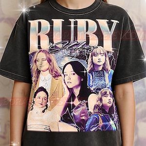 Puede incluir: Camiseta gris oscuro con el texto "RUBY Stokes" y un collage de imágenes de la actriz. El diseño tiene un aspecto vintage y desgastado con una paleta de colores descoloridos.