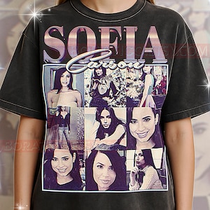 May include: Dark gray t-shirt featuring a collage of images of Sofia Carson. The word "SOFIA" is printed in large, stylized letters above "Carson". The shirt has a vintage, worn look.