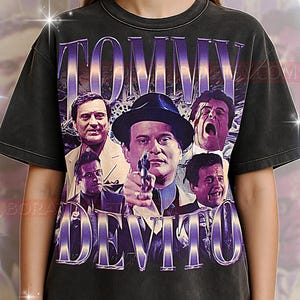 Puede incluir: Camiseta negra con un gráfico de estilo vintage de la película "Goodfellas", con el texto "TOMMY DEVITO" en morado. El diseño incluye imágenes de actores de la película.