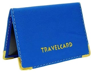 May include: A blue travel card holder with gold accents. The holder is made of a textured material and features the word "TRAVELCARD" in gold lettering. The edges are stitched with white thread.