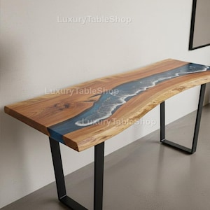 Può includere: Una consolle in legno con un design a bordo vivo. Il tavolo presenta un fiume di resina epossidica blu al centro, con dettagli di onde bianche. Il tavolo ha gambe in metallo nero e il testo "Luxury TableShop".
