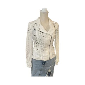 May include: White eyelet jacket with a classic asymmetrical zip closure and multiple zippered pockets. The jacket features long sleeves and a notched collar. The jacket is displayed on a mannequin.