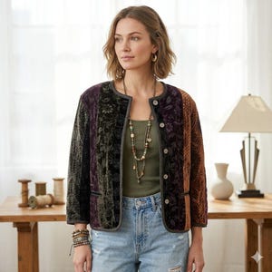 Puede incluir: Chaqueta patchwork con estampado floral en tonos morado, verde y marrón. La chaqueta tiene cuello redondo, cierre de botones y ribete gris. La modelo lleva un top verde y vaqueros azules.