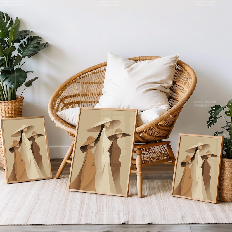 May include: Three framed art prints featuring a minimalist illustration of figures in wide-brimmed hats and long coats. The artwork uses a palette of beige, brown, and cream tones. The prints are displayed near a wicker chair and potted plants.