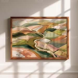 May include: A framed landscape painting with a winding road through rolling hills. The artwork features a palette of soft greens, pinks, and oranges, creating a serene and naturalistic scene. The frame is made of wood.