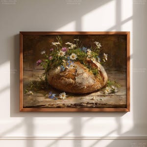 May include: A framed painting depicts a loaf of bread filled with wildflowers. The bread is a golden brown color, and the flowers are white, pink, and blue. The painting is set on a wooden table.