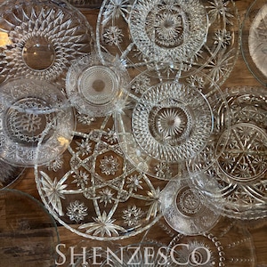 Puede incluir: Vista cenital de varios platos de vidrio transparente con intrincados diseños de estrellas y geométricos. Los platos están dispuestos sobre una superficie de madera. El texto "SHENZESCO" es visible en la parte inferior izquierda.