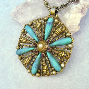 May include: A gold tone pendant necklace with a turquoise and pearl flower design. The pendant features a circular design with turquoise stones and pearls around a central pearl.