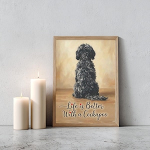 Könnte beinhalten: Ein gerahmter Druck mit einem schwarzen Cockapoo-Hund von hinten, mit dem Text "Life is Better With a Cockapoo". Das Kunstwerk befindet sich in einem Holzrahmen und vor einem neutralen Hintergrund. Zwei weiße Kerzen sind im Vordergrund.