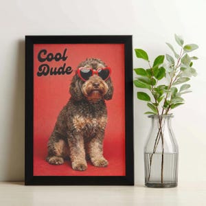 Può includere: Stampa incorniciata con un cane marrone e beige con occhiali da sole a forma di cuore. Il cane è su uno sfondo rosso, con la scritta "Cool Dude" in bianco. Un vaso di vetro trasparente con foglie verdi a destra.