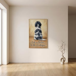 Könnte beinhalten: Ein gerahmter Druck mit einem Cockapoo-Hund mit schwarz-weißem Fell, von hinten gesehen. Der Text "Life is Better With a Cockapoo" ist in Schreibschrift geschrieben. Das Kunstwerk wird in einem Raum mit Holzboden ausgestellt.