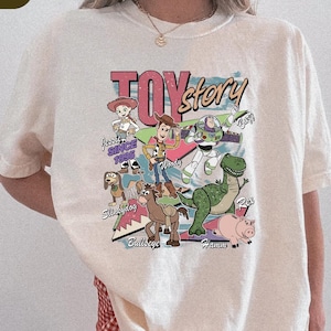 A person wearing a white t-shirt with a colorful graphic of characters from the Toy Story movie.