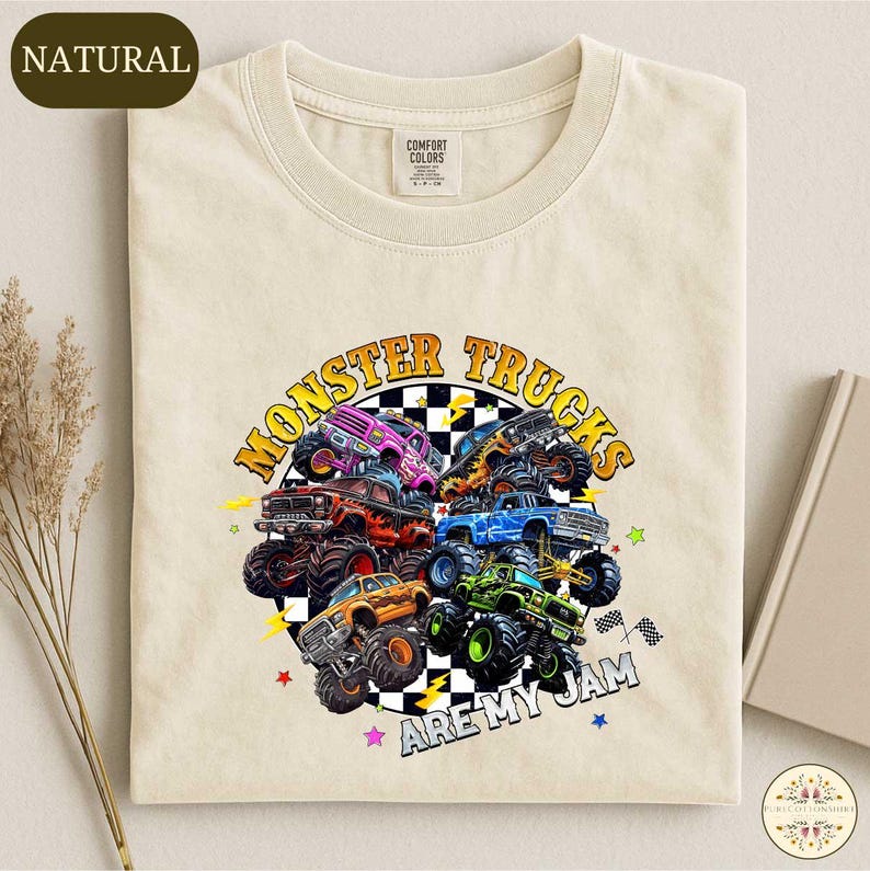 a white t-shirt with a colorful graphic design depicting various monster trucks.