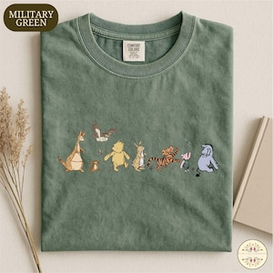 A green t-shirt with a line of cartoon animal characters printed on it, including a kangaroo, a bear, a tiger, a pig, and a lion.