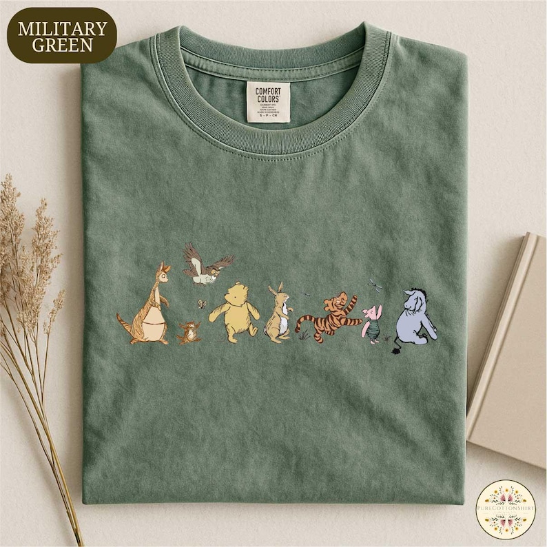 A green t-shirt with a line of cartoon animal characters printed on it, including a kangaroo, a bear, a tiger, a pig, and a lion.