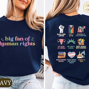 May include: Navy blue sweatshirt with the text "big fan of human rights" in colorful letters on the front. The back of the shirt features various social justice symbols and phrases, including "Black Lives Matter" and "Love is Love."
